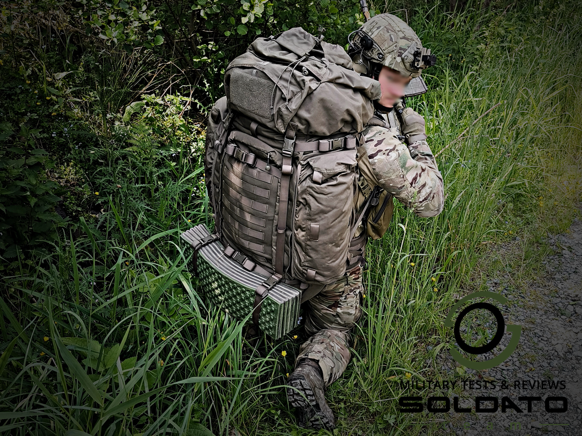 Voják se zbraní v terénu s batohem Snigel 100l Backpack na zádech. 
