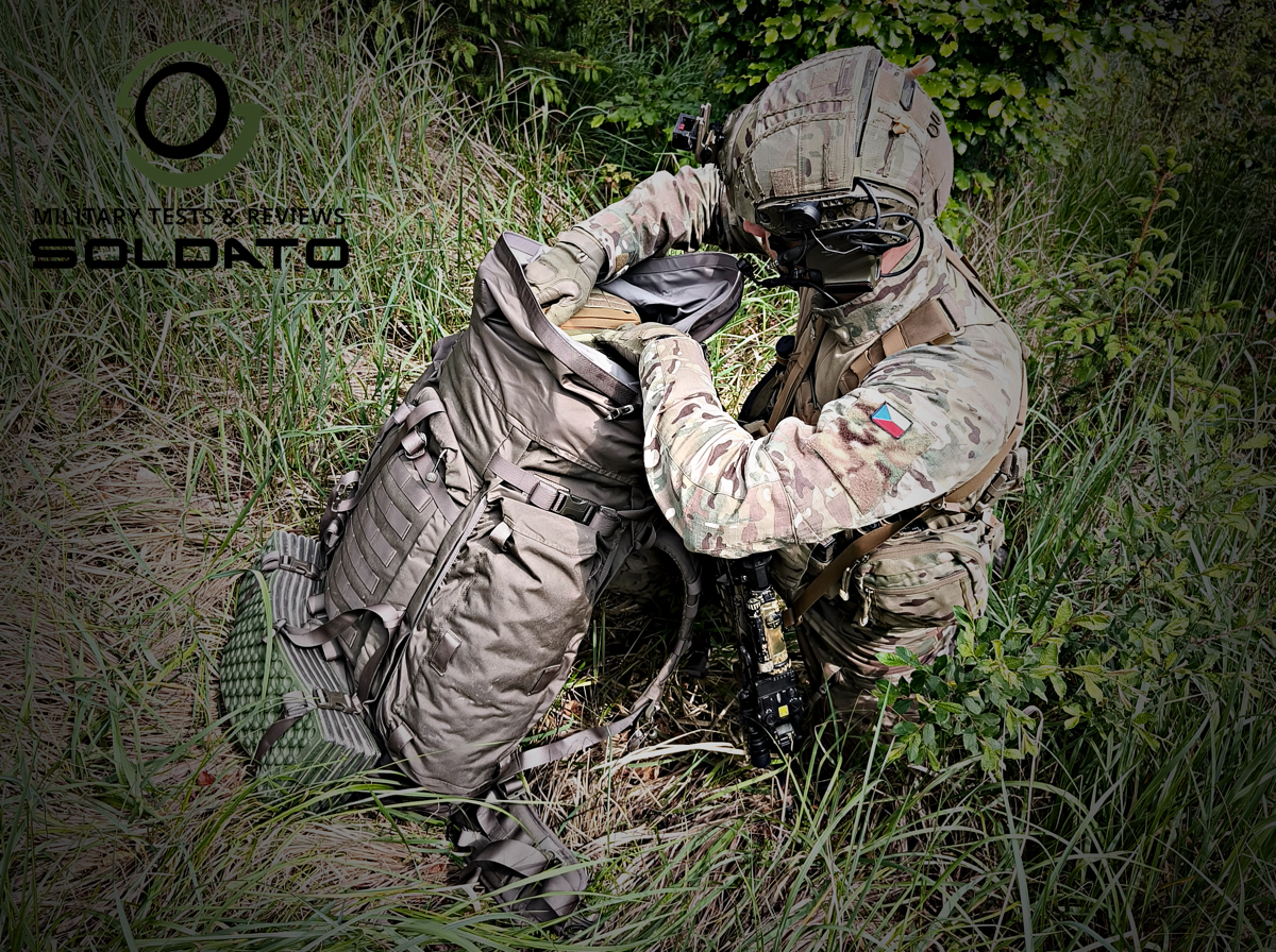 Voják v kleče vytahuje vybavení z komínové části batohu Snigel 100l. 